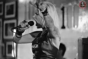 A chaotic gig captured in a black and white photo, featuring a woman singing into a microphone.