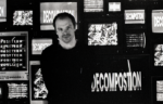 A person stands in front of multiple screens displaying "DECOMPOSITION" and abstract graphics in a dark room, capturing the intense energy of Choke Chain’s new release, Decomposition EP.