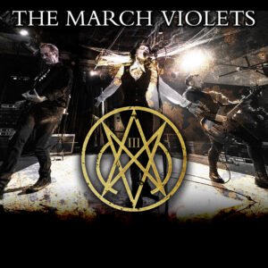 Three musicians perform on stage under bright lights, with THE MARCH VIOLETS text and a striking gold emblem prominently displayed at the centre.